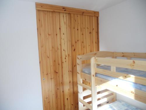 a bedroom with a wooden wall and a bunk bed at les gentianes in La Salle Les Alpes
