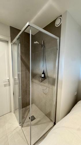 a shower with a glass door in a bedroom at Seanest - North Sea Stays in De Haan