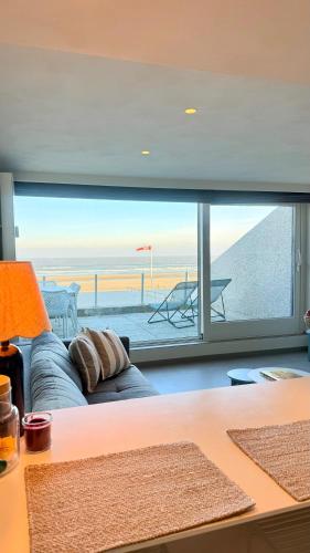 a living room with a couch and a view of the ocean at Seanest - North Sea Stays in De Haan