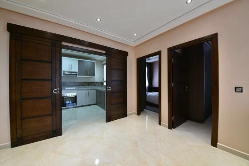 a room with two wooden doors and a kitchen at Bellington Appart Hôtel in Saïdia