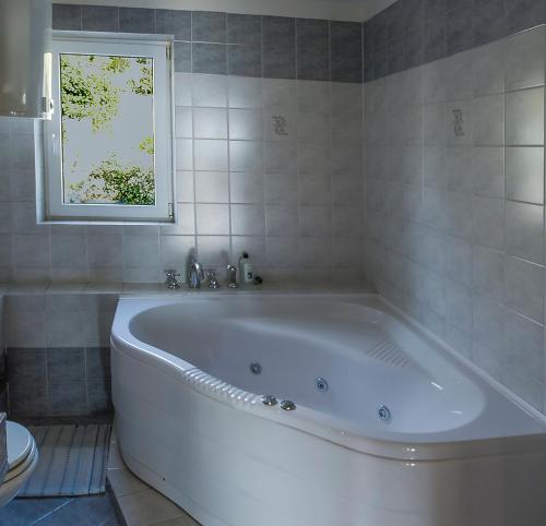 a white bath tub in a bathroom with a window at Holiday Home Marija with Pool & Garden & Amazing Sea View in Dramalj