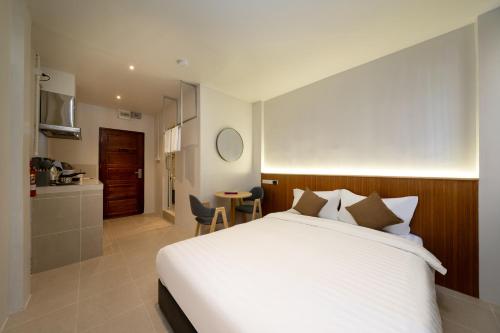 a bedroom with a large white bed and a kitchen at OH Suites 72 in Bangkok