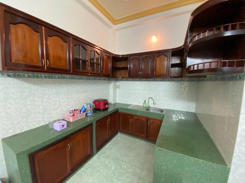 eine Küche mit Holzschränken und einer grünen Arbeitsplatte in der Unterkunft Khách sạn K-Trang APARTMENT in Cần Thơ