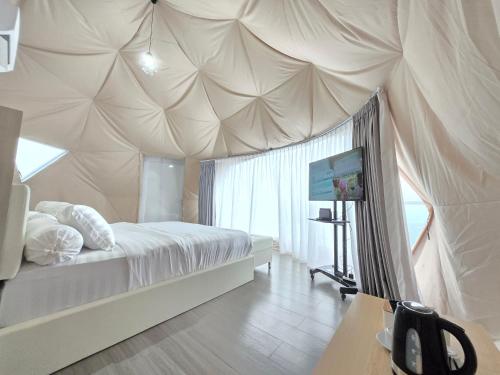 a bedroom with a tent with a bed and a table at Anemos Resort By Tamastu in Pasirpogor