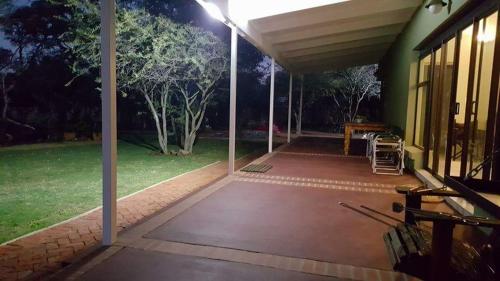 an outdoor patio at night with a table and a bench at Crimson Bush Lodge in Klipdrift