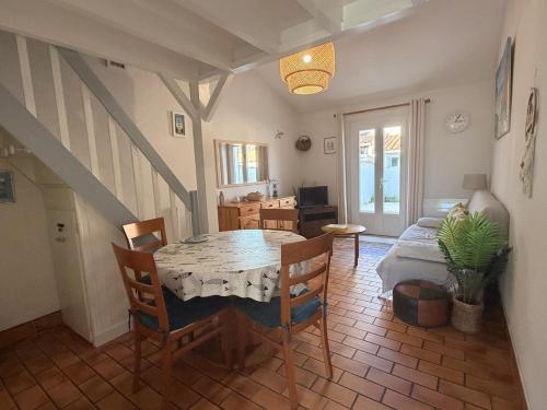 a dining room with a table and chairs and a couch at Les Sables in Saint-Georges-dʼOléron