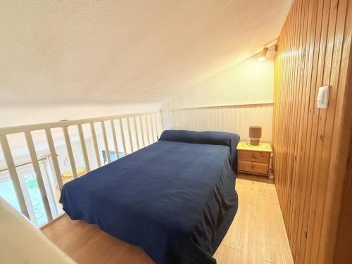 a bedroom with a bed with a blue blanket on it at Les Sables in Saint-Georges-dʼOléron