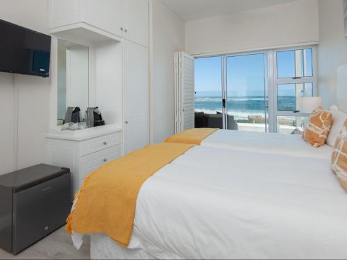 una camera bianca con un grande letto e una grande finestra di Absolute Ocean Boutique Guesthouse a Hermanus