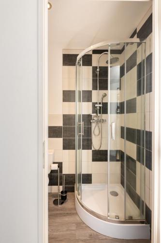 a glass shower in a bathroom with black and white tiles at Studio Chambre St Genest Malifaux in Saint-Genest-Malifaux
