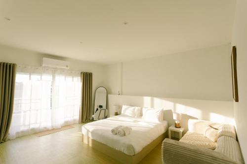 une chambre blanche avec un lit et une chaise dans l'établissement PANI Place Khaolak, à Khao Lak