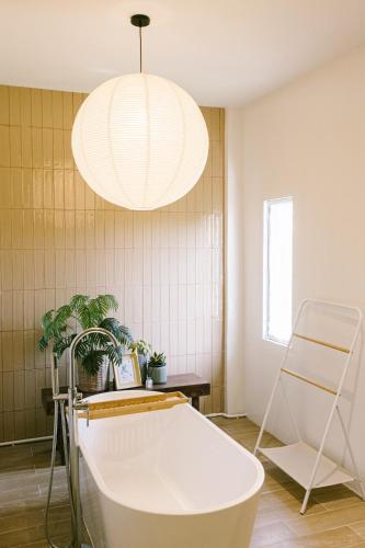 a bathroom with a white tub and a light fixture at PANI Place Khaolak in Khao Lak