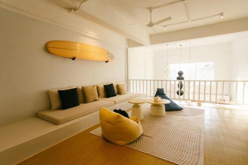 - un salon avec un canapé et une planche de surf sur le mur dans l'établissement PANI Place Khaolak, à Khao Lak