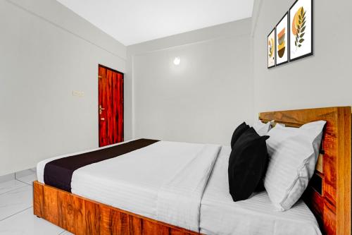une chambre avec un lit avec des oreillers noirs et blancs dans l'établissement Hotel O THAIBA RESIDENCY, à Kuttyādi