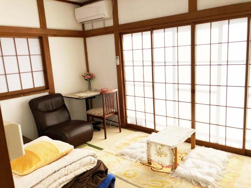 una stanza con un letto, una sedia e delle finestre di The Village House 1 a Hadano