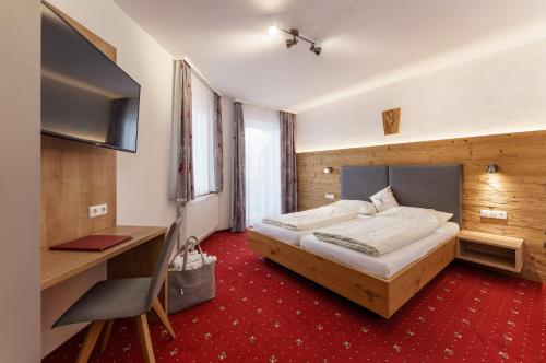 a bedroom with a bed and a desk and a computer at Hotel Moser in Schladming