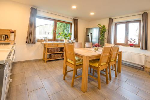 een keuken en eetkamer met een houten tafel en stoelen bij FEWO 2 zur schönen Aussicht in Hinterschmiding