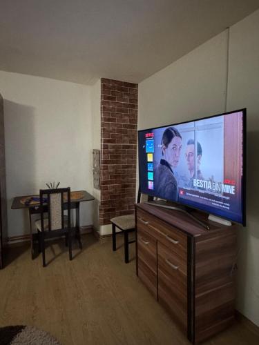 een grote flatscreen-tv op een houten standaard in een woonkamer bij Căsuța din Vale in Râșca