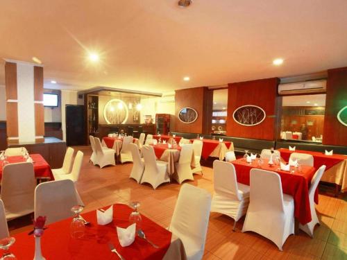 a restaurant with red and white tables and white chairs at Alexander Hotel Tegal in Tegal
