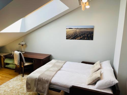 een slaapkamer met een bed en een bureau op zolder bij Jurmaris in Neringa