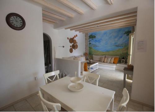 a dining room with a table and a clock on the wall at Theros Casa Logaras in Piso Livadi