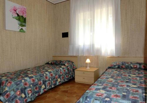 una camera d'albergo con due letti e una finestra di Milano Sabbiadoro a Lignano Sabbiadoro