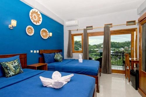 een slaapkamer met 2 bedden en een blauwe muur bij Hotel Bonne Nuit in Labuan Bajo