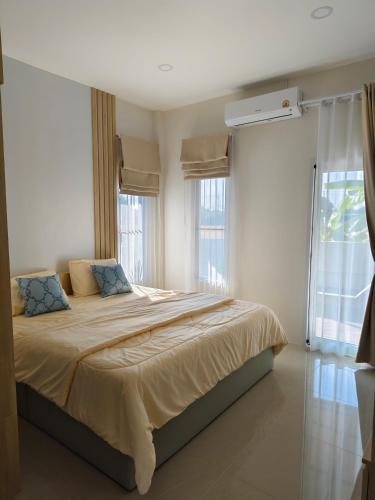 a bedroom with a large bed with two windows at รักตะวัน เวียงพันแสน in Hang Dong