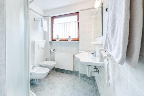 a white bathroom with a toilet and a sink at Pension Haus am See in Naz-Sciaves