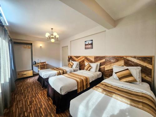een hotelkamer met 3 bedden en een kroonluchter bij Nyadha House Bed & Breakfast in Pātan