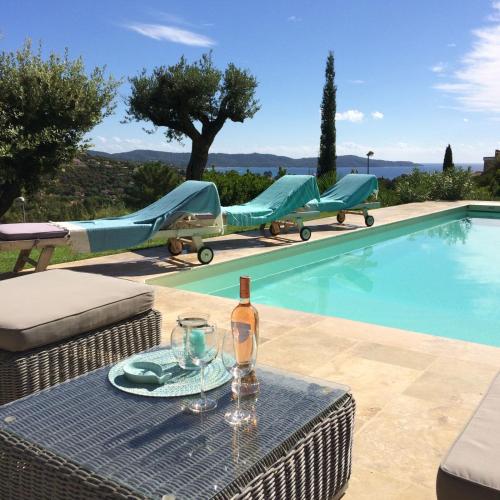 - une bouteille de vin assise sur une table près de la piscine dans l'établissement Villa 