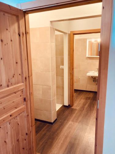 ein Badezimmer mit Holztür und Waschbecken in der Unterkunft primiero-suite 45mq in Transacqua