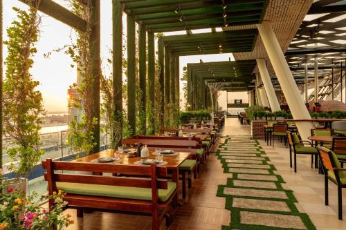 a restaurant with wooden tables and chairs and plants at Aloft Abu Dhabi in Abu Dhabi