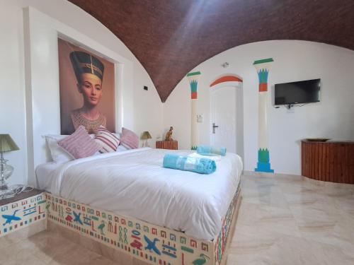 a bedroom with a large bed with a painting on the wall at ATON PALACE Luxor in Luxor