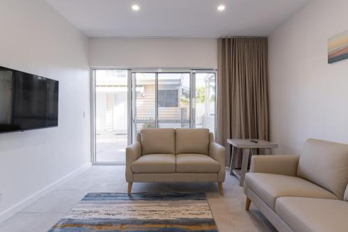 a living room with two chairs and a couch at Esplanade Apartments at West Beach in Adelaide