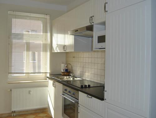 a kitchen with white cabinets and a sink and a window at Adoreo Apartments & Suites in Leipzig