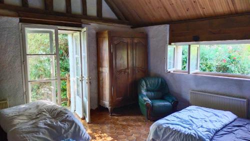 une chambre avec un lit, une chaise et des fenêtres dans l'établissement Petit Moulin Renaissance, à Coulongé