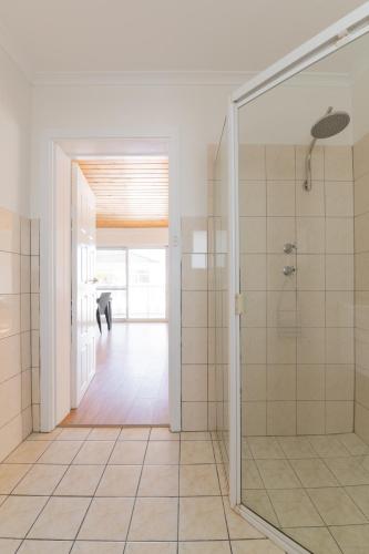 a bathroom with a walk in shower and a glass door at Esplanade Apartments at West Beach in Adelaide