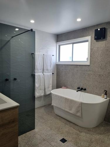 a bathroom with a tub and a shower and a window at Sheik Oasis in Lightning Ridge
