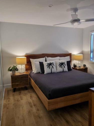 a bedroom with a bed with two lamps and two palm trees at Sheik Oasis in Lightning Ridge