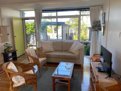 a living room with a couch and a tv at Shelly Beach Townhouse in East Ballina