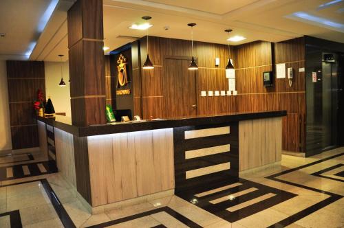 a bar in a lobby with wood paneling at Ouro Minas Plaza Hotel in Aparecida