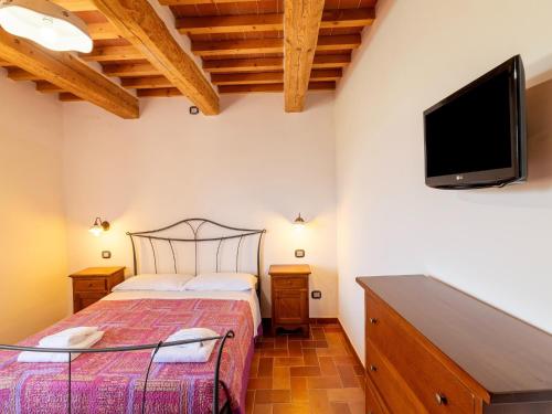 a bedroom with a bed and a flat screen tv at Apartment in a farmhouse with 2 swimming pools in Cagli