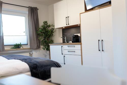 a bedroom with a bed and a kitchen with white cabinets at Heu22 Herbstgold in Farchant