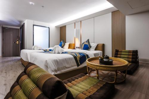 een hotelkamer met twee bedden en een tafel en stoelen bij Marquis Hotel in Ban Bang Toei (1)