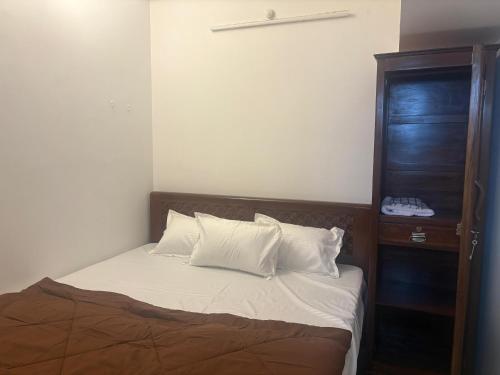 a bedroom with a bed with white sheets and a wooden cabinet at Varson Stay in Pondicherry