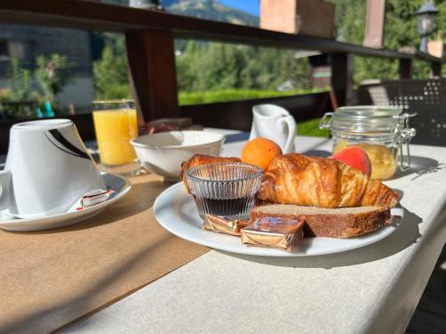 une table avec une assiette de croissants, de pain et d'oranges dans l'établissement Hôtel le Christiania, à Arêches