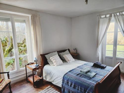 ein Schlafzimmer mit einem Bett und zwei Fenstern in der Unterkunft Demeure périgourdine, prairies et accès rivière in Cherveix-Cubas