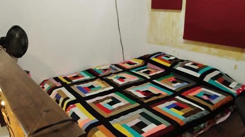 a bed with a colorful quilt on it in a room at Beco do Curupira Bangalô in São Luiz do Paraitinga