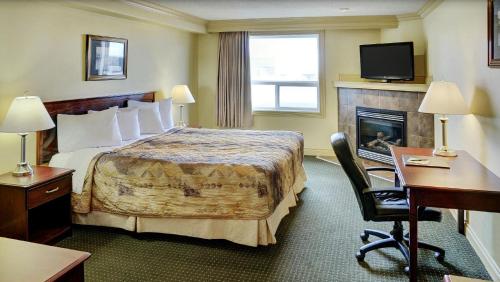 a hotel room with a bed and a fireplace at Nova Inn Peace River in Peace River