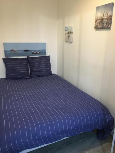 een bed in een kamer met een blauw gestreept laken bij Petit T2 de charme in Eysines